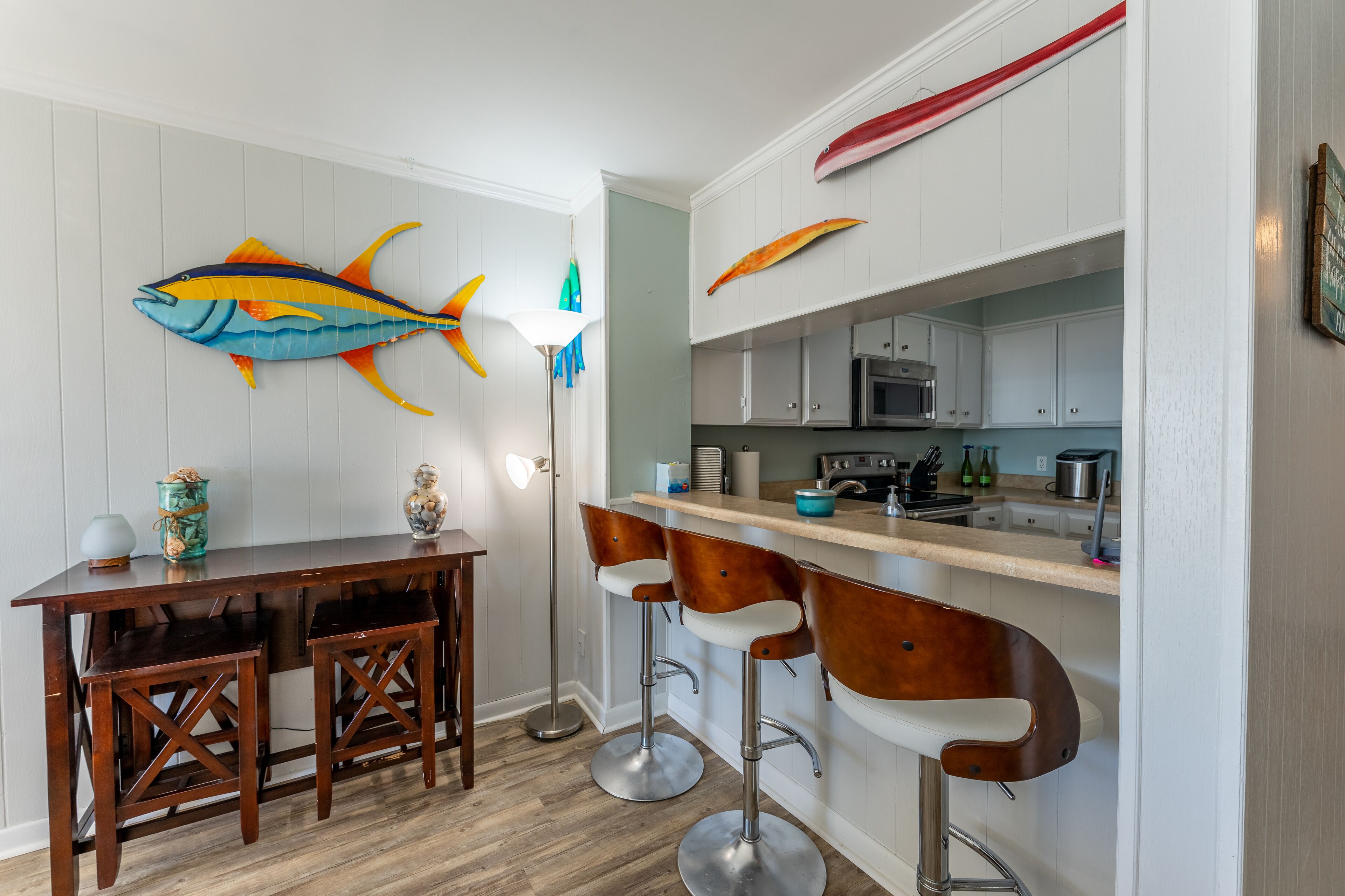 A kitchen with white cabinets, a wooden table, and two bar stools.