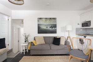 Relax in this stylish living room with a sofa, side table, and comfortable chair, perfect for unwinding.