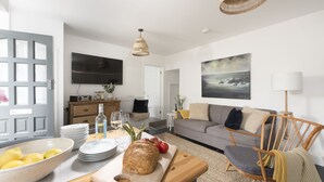 Una sala de estar moderna con una mesa de comedor de madera, un sofá y un televisor montado en la pared.