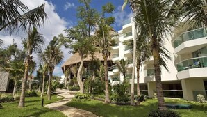 A resort with a pathway, palm trees, and a modern building with balconies.