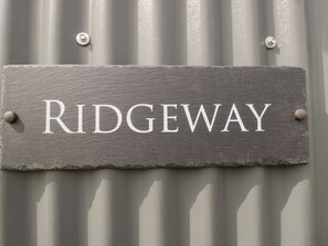A slate sign with the word "RIDGEWAY" mounted on a corrugated metal wall.