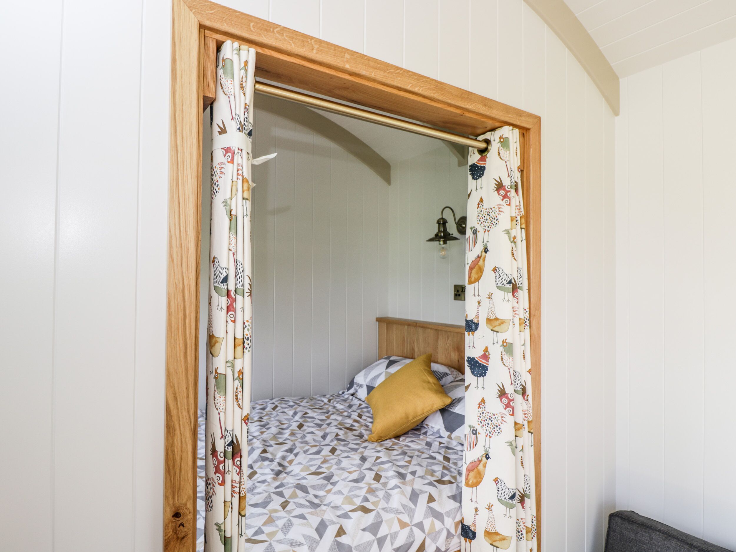 A bedroom with a bed, a wooden headboard, and patterned curtains.