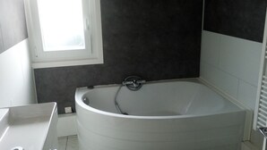 Une salle de bain moderne avec une baignoire sur pieds, une fenêtre et un sol carrelé.