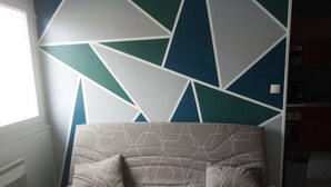 Un salon moderne avec un canapé aux motifs géométriques et un mur orné d’un décor géométrique.