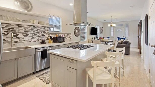 Una cocina moderna con una isla central, electrodomésticos de acero inoxidable y un salpicadero de azulejos.