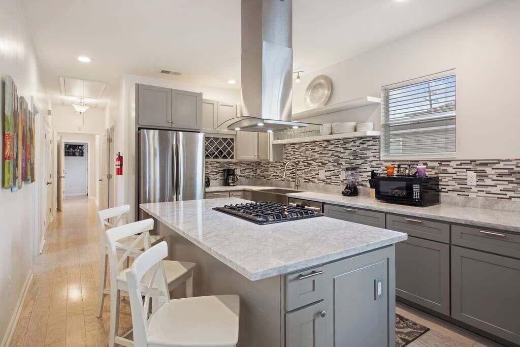 Una cucina moderna con isola centrale, elettrodomestici in acciaio inossidabile e zoccolo paraschizzi decorato.