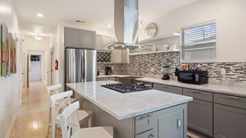 Una cucina moderna con isola centrale, elettrodomestici in acciaio inossidabile e zoccolo paraschizzi decorato.
