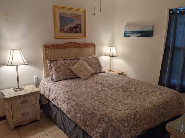 A bedroom with a patterned bedspread, two bedside tables with lamps, a headboard, and a framed picture on the wall. - Lake front cottage (Salt Springs)