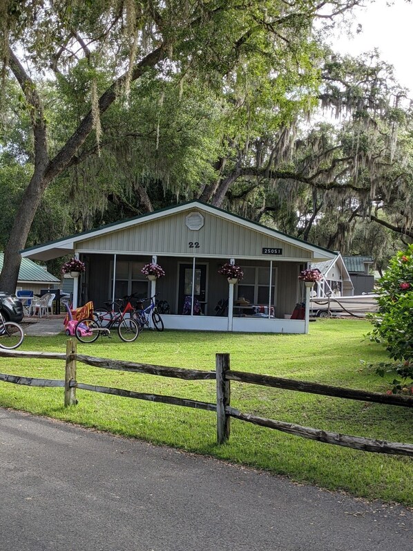 A small, single-story building with a porch, numbered 22, and a sign reading "25051". - Lake front cottage (Salt Springs)