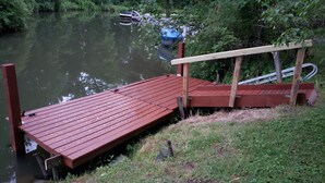A wooden dock extending into a calm river, surrounded by lush greenery. - Cozy Cottage (Ashville)