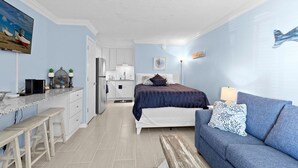 Een compacte kamer met een bed, een slaapbank, een kitchenette en een eettafel.