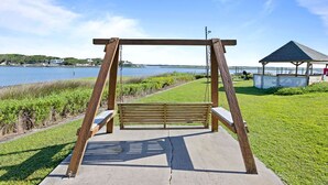 Een houten schommelset met banken, een prieel en uitzicht op het water en het landschap.