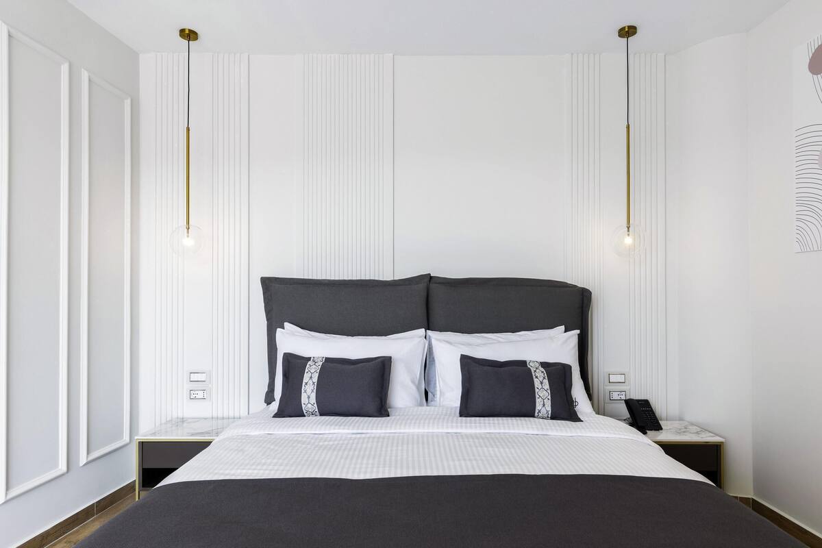 Een moderne hotelkamer met een groot bed, nachtkastjes, een telefoon en een wandlamp.