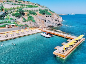 Une station balnéaire dotée d’une piscine, de chaises longues et d’un quai avec des bateaux.
