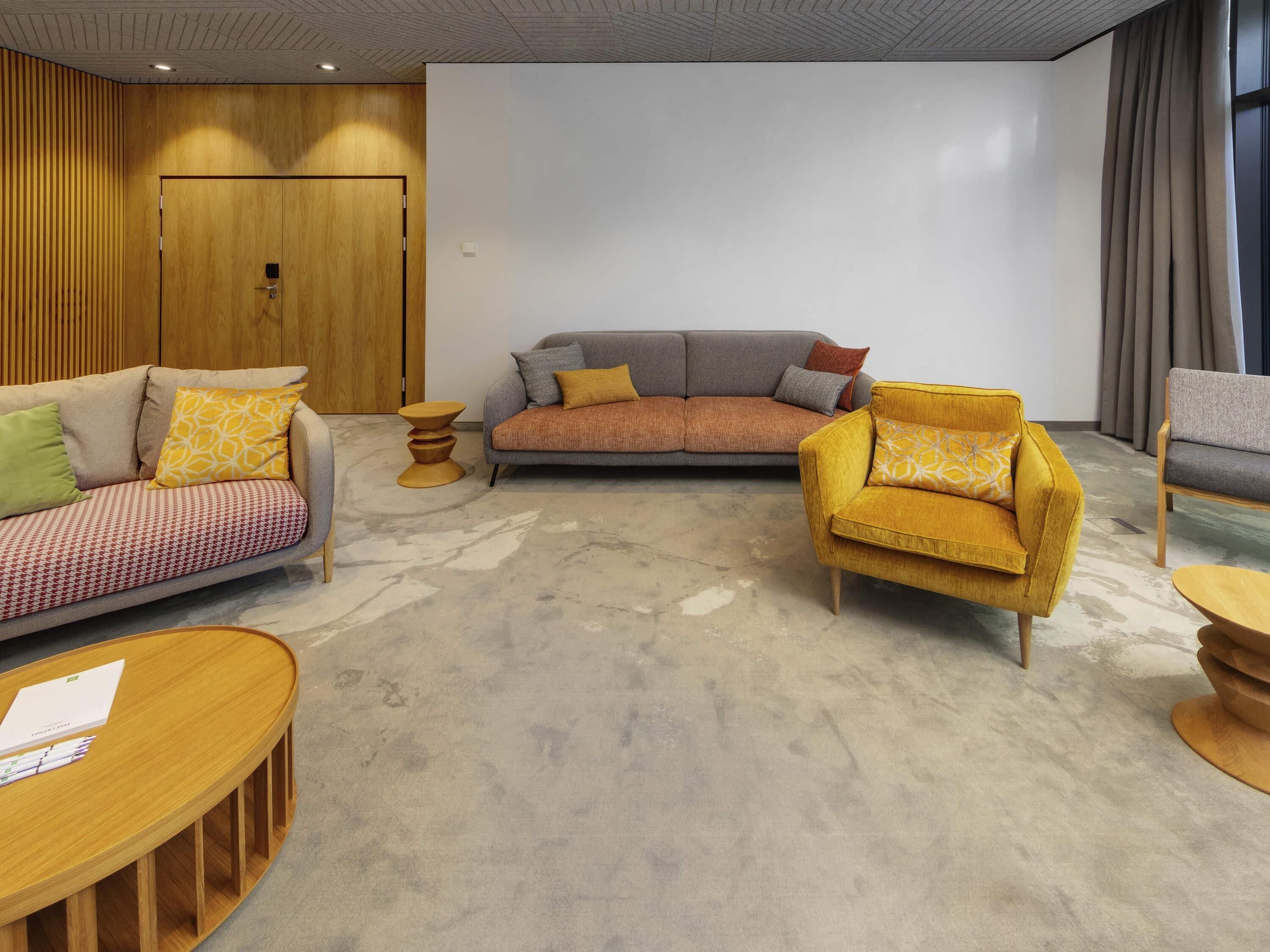 Ein modernes Wohnzimmer mit einer Couch, Sesseln und einem Couchtisch.