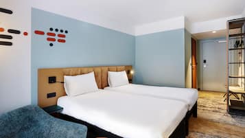 Ett hotellrum med en säng, en stol, ett litet bord och en garderob.
