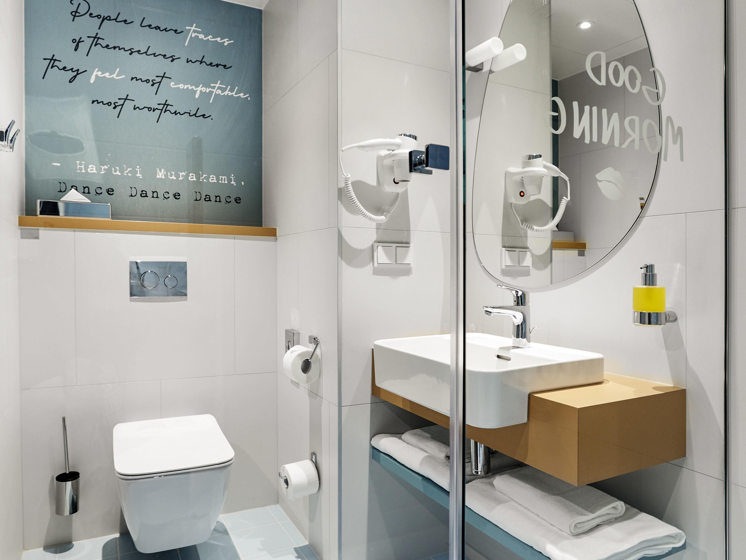 A modern bathroom with a toilet, a sink, a mirror, and a towel rack.