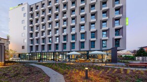 Un hotel moderno con una serie de balcones, mobiliario exterior y un jardín bien cuidado.