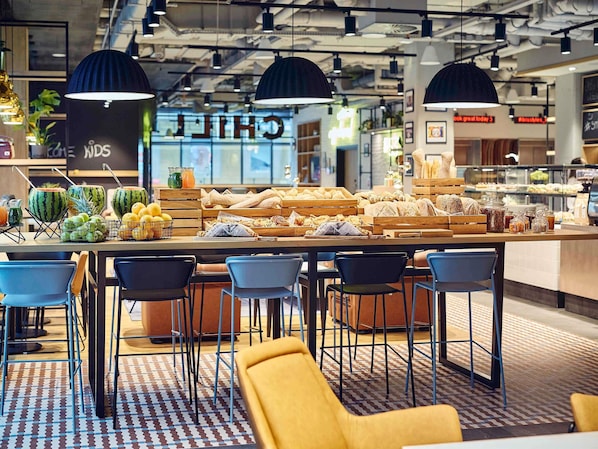A breakfast bar with a variety of foods and drinks, surrounded by modern chairs and pendant lighting. - ibis Styles Kraków Centrum (Kraków)