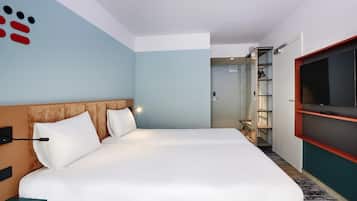 A hotel room with a large bed, a TV mounted on the wall, and a wardrobe.