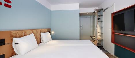 A hotel room with a large bed, a TV mounted on the wall, and a wardrobe.