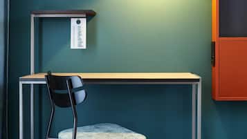 A room with teal walls, a desk with a chair, and a cabinet.