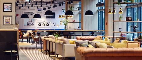 A modern interior with seating areas, tables, and decorative plants.