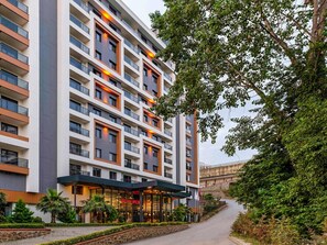 A multi-story hotel with a modern facade, large windows, and a well-maintained outdoor area with a pathway and greenery. - Mövenpick Hotel Trabzon (Trabzon)