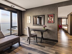A modern hotel room with a large window, a dining table, a chair, a bed, and a mirror. - Mövenpick Hotel Trabzon (Trabzon)