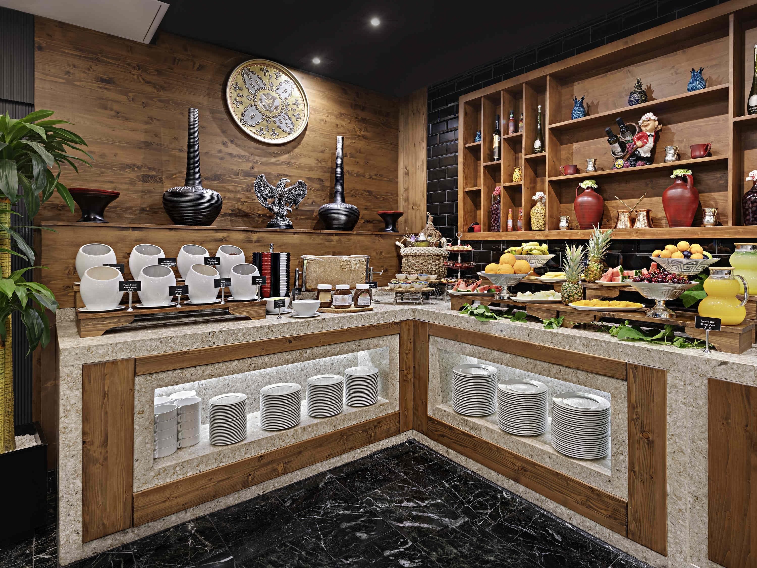 Montaje de bufé con diversos platos, una pared decorativa y un estante de madera con objetos.