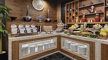 Montaje de bufé con diversos platos, una pared decorativa y un estante de madera con objetos.
