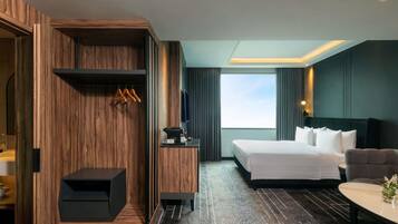 A hotel room with a bed, a sofa, a desk, and a wardrobe.