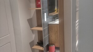 Un baño moderno con un espejo integrado, un lavabo y un cesto de basura rojo.