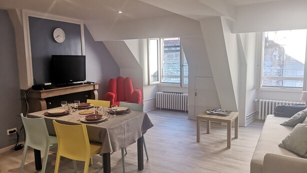 Una sala de estar moderna con comedor, televisor, una butaca roja y un sofá.