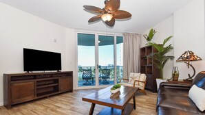 Un salon équipé d’un téléviseur à écran plat, d’une table basse en bois, d’un canapé en cuir et d’un ventilateur de plafond.