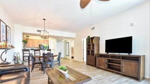 Un salon spacieux avec une table basse en bois, un canapé en cuir et un téléviseur posé sur un meuble en bois.