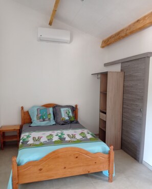 Ein Schlafzimmer mit einem hölzernen Bett, einem Nachttisch, einem Kleiderschrank und einer Klimaanlage an der Wand.