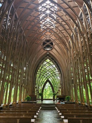 Interior de una catedral con un techo abovedado alto, hileras de bancas y un pasillo central que conduce a un altar.