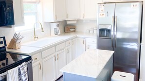 A modern kitchen with white cabinets, stainless steel appliances, and a marble countertop. - Relaxing Coastal Inspired Cottage, short walk from the lake! (Ashtabula)