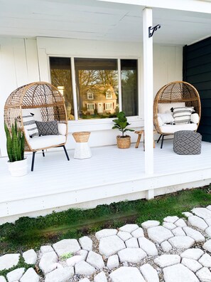 A porch with two wicker chairs, a small table, and a potted plant. - Relaxing Coastal Inspired Cottage, short walk from the lake! (Ashtabula)
