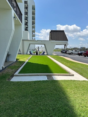Un edificio moderno con un diseño arquitectónico único, que cuenta con un área verde central con asientos y un estacionamiento al fondo.