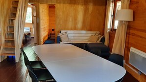 Un intérieur en bois avec une longue table, des chaises, un canapé et un escalier.
