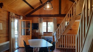Un intérieur en bois comprenant une table à manger, des chaises, un escalier et un téléviseur.