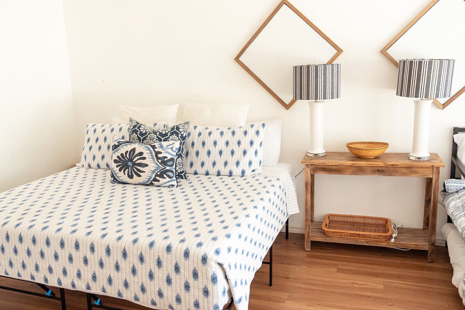 Une chambre à coucher avec un lit, des oreillers, une table de chevet, une lampe et un miroir.