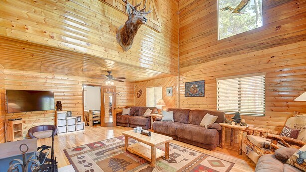 L’intérieur d’un chalet en rondins, avec une tête de cerf accrochée au mur, des murs en bois, un téléviseur et un coin salon confortable.