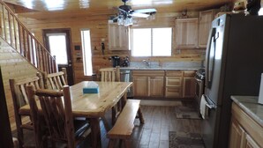 L’intérieur d’un chalet en bois comprend un coin repas, une cuisine et un escalier.