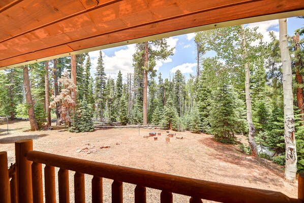 A wooden deck overlooking a forested area with a dirt ground and scattered rocks.