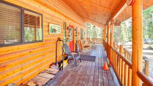 Une cabane en bois avec un porche couvert, des fauteuils à bascule et une pancarte sur laquelle on peut lire : « Ne réveillez pas l’ours. »
