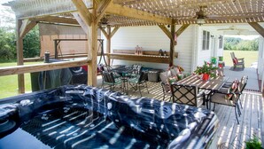 En træterrasse med jacuzzi, udendørs møbler og et pergola-tag.