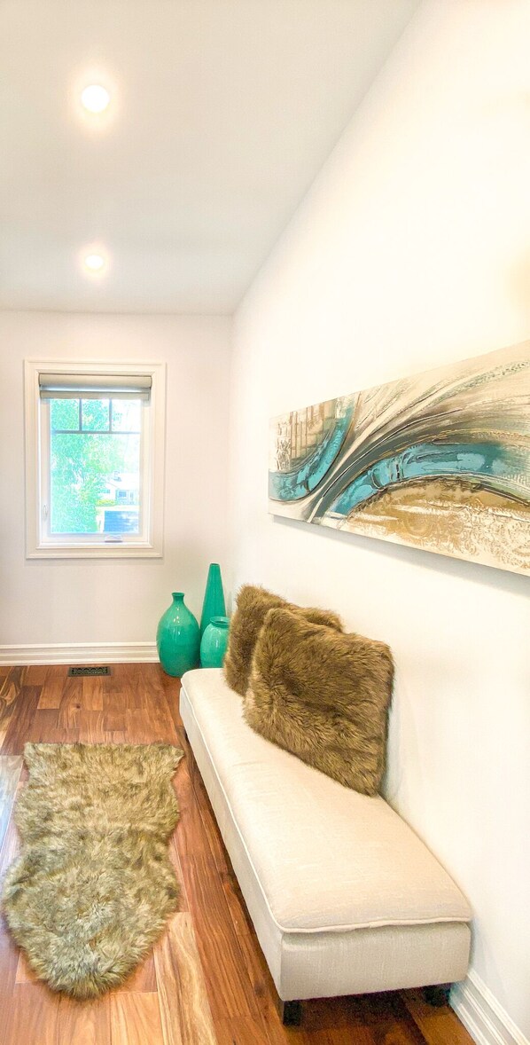A room with a white sofa, a green rug, and a large abstract painting on the wall. - Luxury stay at a Beach House • Sleeps 8 • Walk to Bay Beach (Crystal Beach)